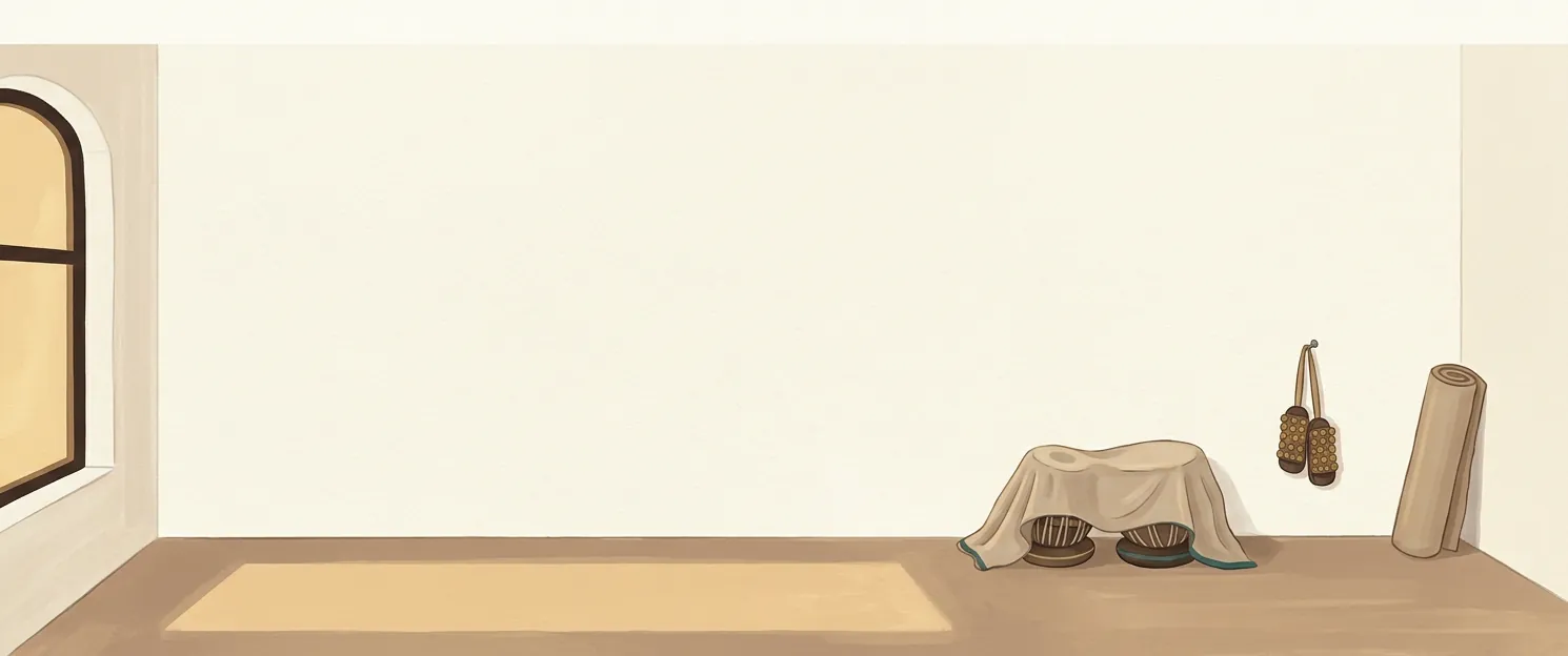 An empty practice room at dusk: a rolled mat against the wall, ghunghroo hung on a nail, a covered tabla in the corner, evening light lying across the floor.